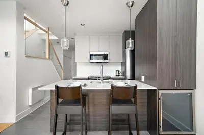 a kitchen with a counter with two chairs and a sink at 3 bedroom Penthouse Great for family vacation in Montréal