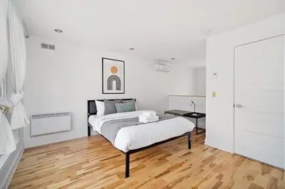 a white bedroom with a bed and a wooden floor at 3 bedroom Penthouse Great for family vacation in Montréal