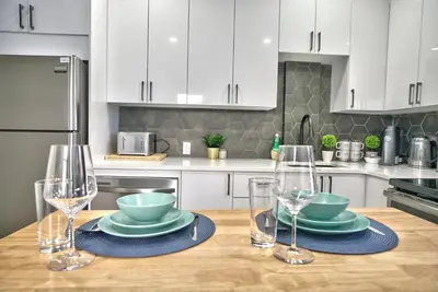 a kitchen with a wooden table with plates and wine glasses at Sherby LUX - Central, Parking, Renovated, Sleeps 6 in Sherbrooke