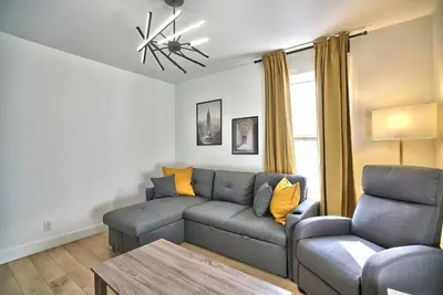 a living room with a gray couch and a table at Sherby LUX - Central, Parking, Renovated, Sleeps 6 in Sherbrooke