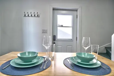 a wooden table with two plates and two wine glasses at Sherby LUX - Central, Parking, Renovated, Sleeps 6 in Sherbrooke