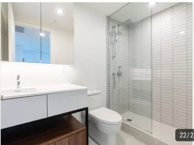 a white bathroom with a toilet and a glass shower at High-End Condo for Rent in Montréal