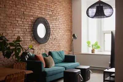 a living room with a blue couch and a brick wall at The Suzanne by Denstays in Montréal