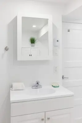 a white bathroom with a sink and a mirror at The Suzanne by Denstays in Montréal