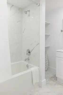 a white bathroom with a tub and a shower at The Suzanne by Denstays in Montréal