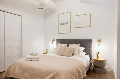 a bedroom with a large bed with white walls at The Suzanne by Denstays in Montréal