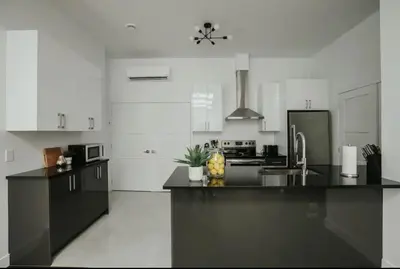 a large kitchen with black counter tops and white cabinets at Stylish and bright 2bdr near St-Hubert Plaza in Montréal