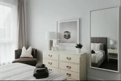 a bedroom with a dresser and a mirror and a bed at Stylish and bright 2bdr near St-Hubert Plaza in Montréal