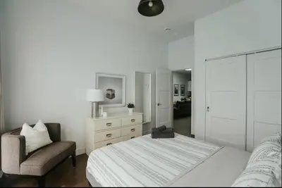 a white bedroom with a bed and a chair at Stylish and bright 2bdr near St-Hubert Plaza in Montréal