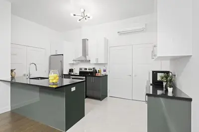 a kitchen with white cabinets and a black counter top at Modern and Cozy 2bdr near St-Hubert Plaza in Montréal