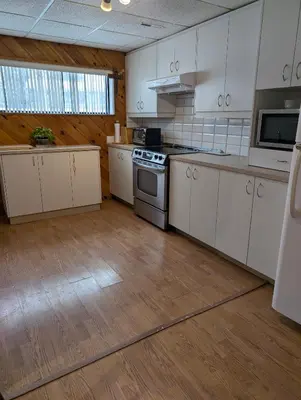 a kitchen with white cabinets and a stove top oven at Style Chalet in Montréal