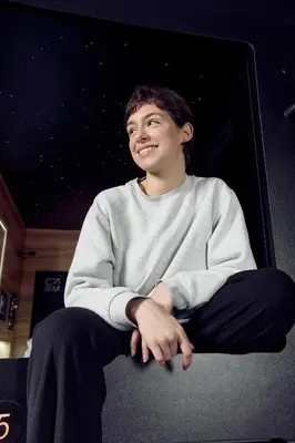a young man sitting in a chair smiling at Capsule Hotel Montreal in Montréal