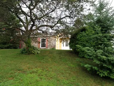 a stone house with a tree in front of it at Paradise Eastern Township cottage in Cowansville