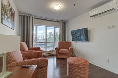 a living room with chairs and a flat screen tv at Le Bijou Airhome in Montréal