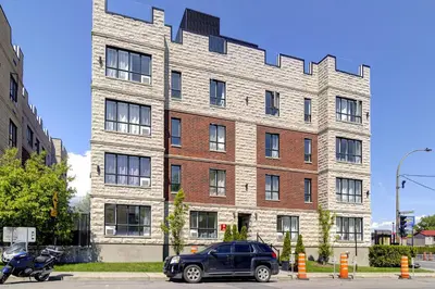 a black car parked in front of a large brick building at Le Bijou Airhome in Montréal