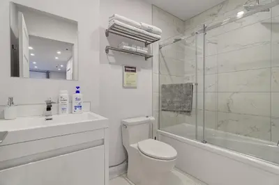 a white bathroom with a toilet and a shower at Le Bijou Airhome in Montréal