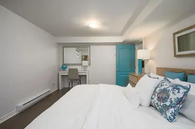 a bedroom with a large white bed and a desk at Tranquille Discret Privé in Laval