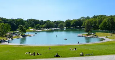 a large lake with people sitting in the grass at Tranquille Discret Privé in Laval