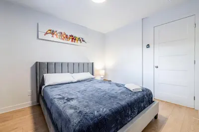 a bedroom with a large bed in a white room at Longueuil New Stylish 3-BDR free parking close to Dix 30&DT in Longueuil