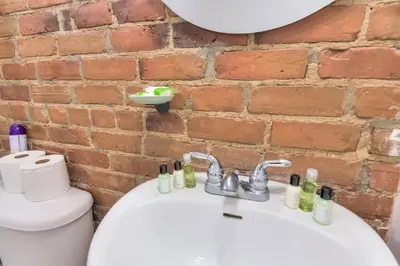 a bathroom with a sink and a toilet and a brick wall at Fox Aparthotel 9 min of Palais Des Congres II in Montréal