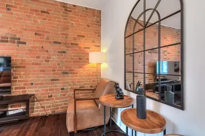 a living room with a brick wall and two tables and a mirror at Fox Aparthotel Palais Des Congres VI in Montréal