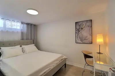 a bedroom with a bed and a desk with a lamp at Private Peaceful Queen Room Free Parking in Saint-Bruno-de-Montarville