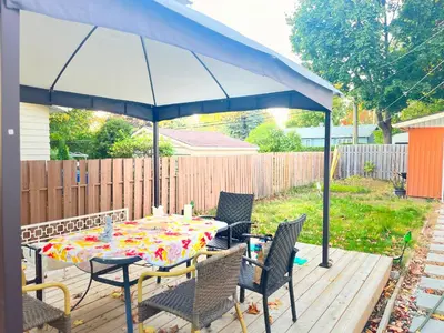 a patio with a table and chairs under a blue umbrella at Private Peaceful Queen Room Free Parking in Saint-Bruno-de-Montarville