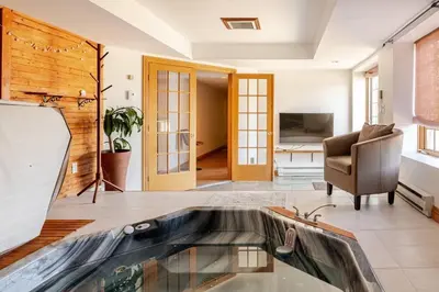 a living room with a tv and a couch and a chair at Waterfront Mansion with Mont-Saint-Hilaire Views, Near Montreal in Beloeil Village