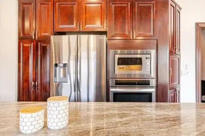 a kitchen with stainless steel appliances and wooden cabinets at Waterfront Mansion with Mont-Saint-Hilaire Views, Near Montreal in Beloeil Village