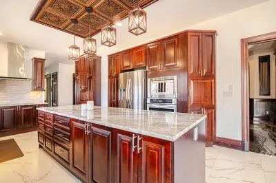a large kitchen with wooden cabinets and a counter top at Waterfront Mansion with Mont-Saint-Hilaire Views, Near Montreal in Beloeil Village