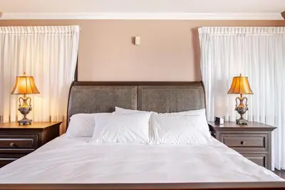 a bedroom with a bed with two nightstands and two lamps at Waterfront Mansion with Mont-Saint-Hilaire Views, Near Montreal in Beloeil Village