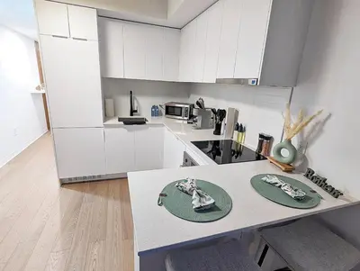 a kitchen with white cabinets and a table at Studio Chic - Centre MTL in Montréal