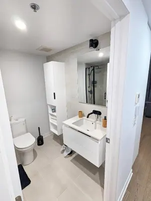 a white bathroom with a toilet and a sink at Studio Chic - Centre MTL in Montréal