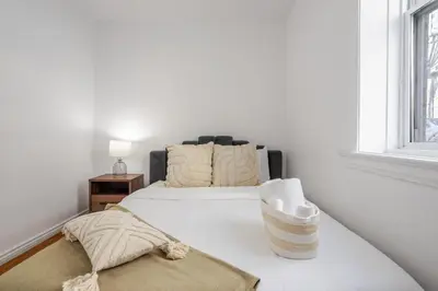 a white bedroom with a bed and a window at Exclusive Loft Living in the Heart of Montreal in Montréal