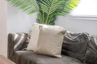 a brown leather couch with a pillow and a palm tree at Exclusive Loft Living in the Heart of Montreal in Montréal