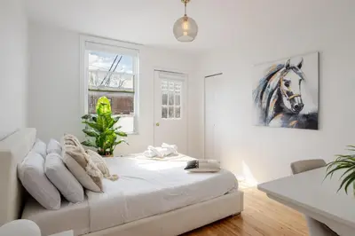 a white bedroom with a bed and a painting of a horse at Bright 2BR in Plateau Mont Royal Downtown in Montréal