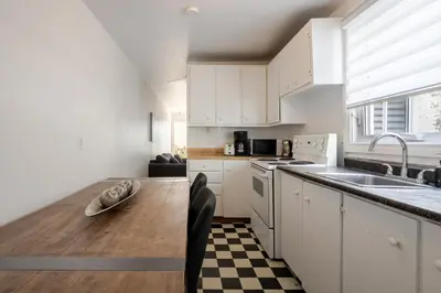 a kitchen with white cabinets and a wooden table at Bright 2BR in Plateau Mont Royal Downtown in Montréal