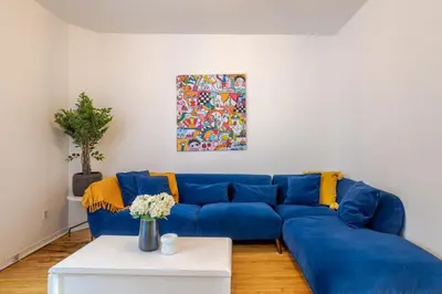 a blue couch in a living room with a painting at Convenient 4BR in Mont Royal Downtown in Montréal