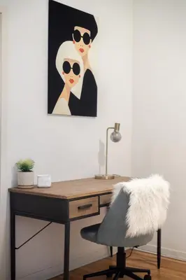 a desk with a chair and a painting of two women at Convenient 4BR in Mont Royal Downtown in Montréal