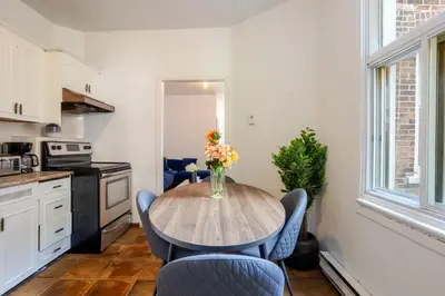 a kitchen with a table with chairs and a vase of flowers at Convenient 4BR in Mont Royal Downtown in Montréal