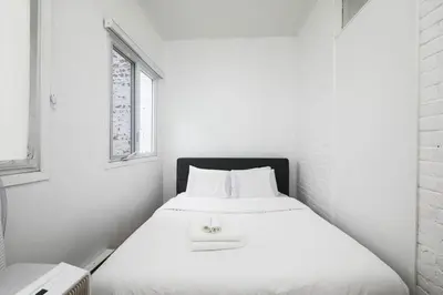 a white bed in a white room with a window at Beautiful apartment in Downtown in Montréal