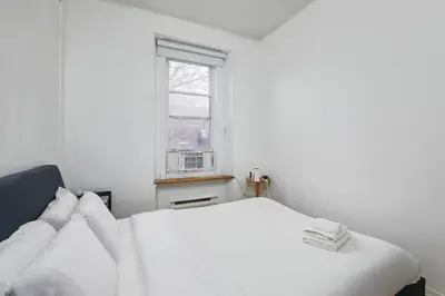 a white bed in a white room with a window at Beautiful apartment in Downtown in Montréal