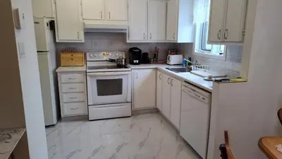 a kitchen with white cabinets and white appliances at Family-Friendly in Quiet Laval Neighborhood in Laval