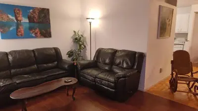 a living room with a leather couch and a table at Family-Friendly in Quiet Laval Neighborhood in Laval