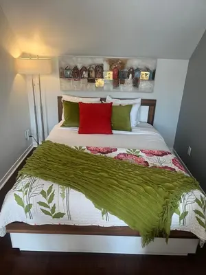 a bed with red and green pillows on it at L'intime loft Studio à Orford in Magog-Orford