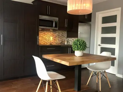 a kitchen with a wooden table and white chairs at L'intime loft Studio à Orford in Magog-Orford