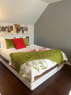 a bedroom with a large bed with red and green pillows at L'intime loft Studio à Orford in Magog-Orford
