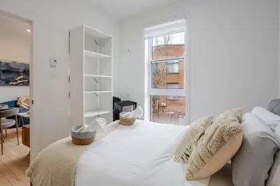 a white bedroom with a bed and a window at Peaceful 1BR Getaway Near MTL Village in Montréal