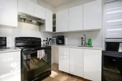 a kitchen with white cabinets and a black oven at Contemporary 2BR Retreat in MTL Village in Montréal