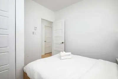 a white bedroom with a bed with two towels on it at Contemporary 2BR Retreat in MTL Village in Montréal